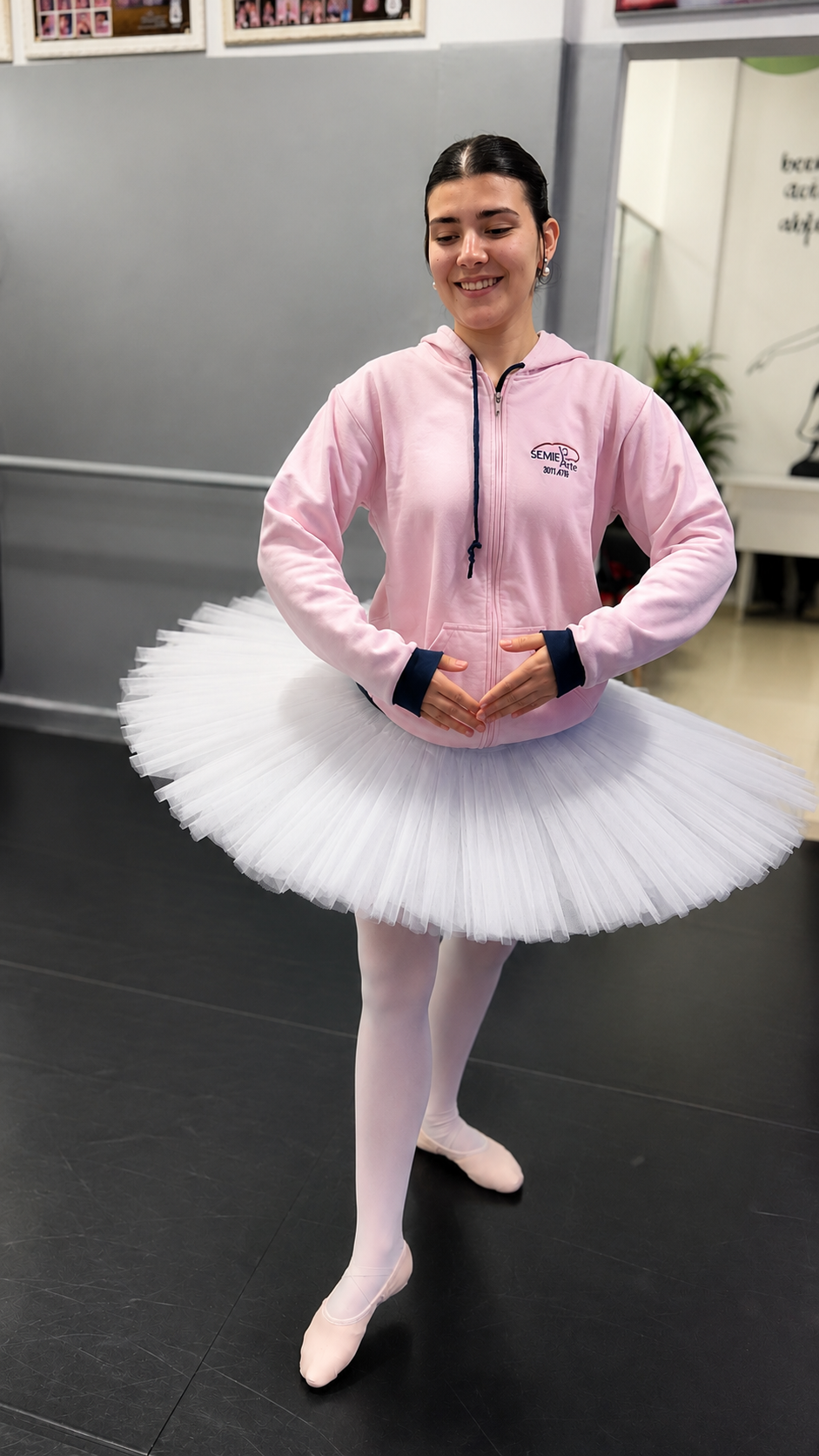 Bailarina da SEMIE Arte sorrindo em tutu branco e moletom rosa